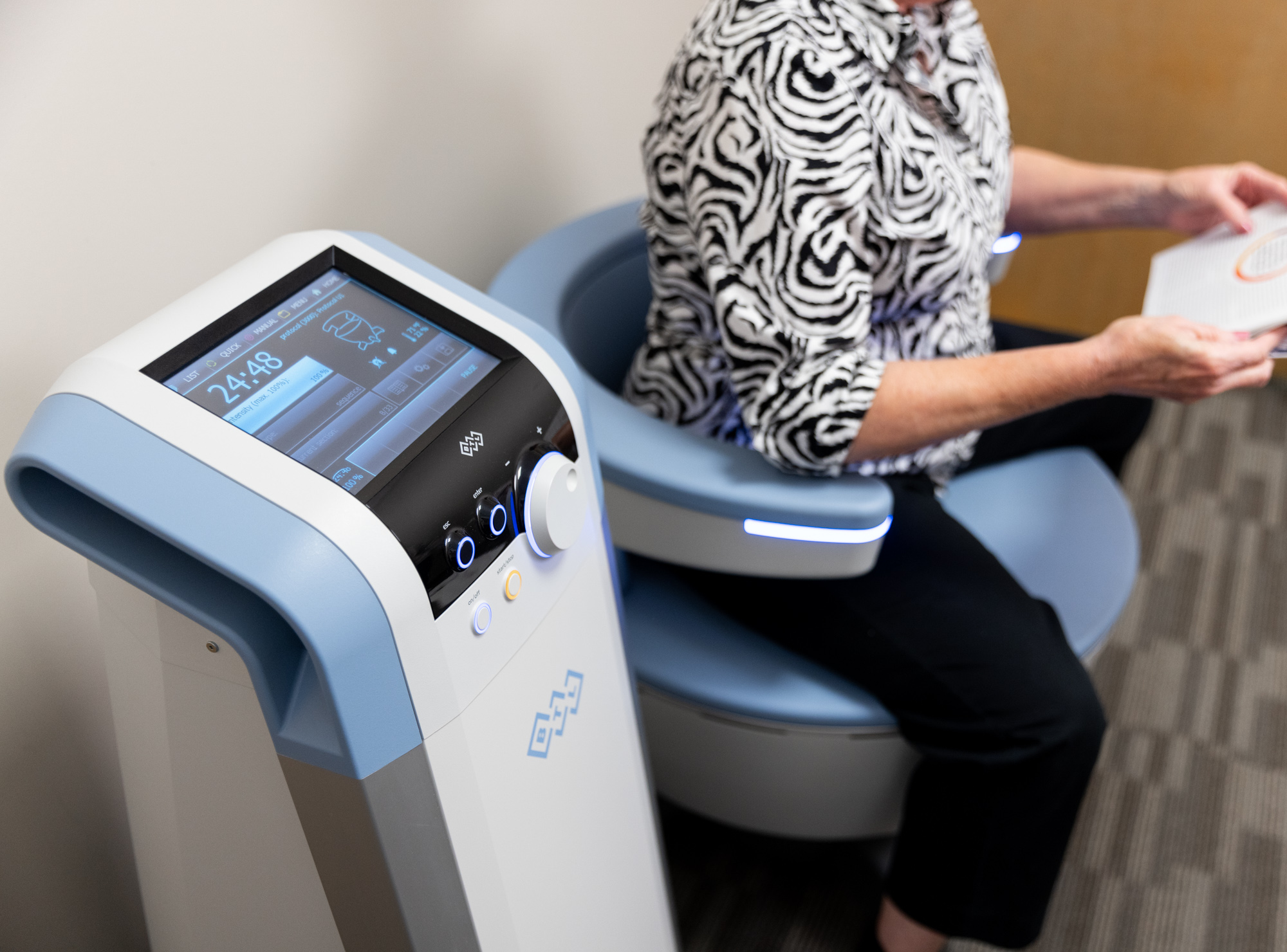 woman sitting on an emsella chair during her visit with a women's health doctor near plano