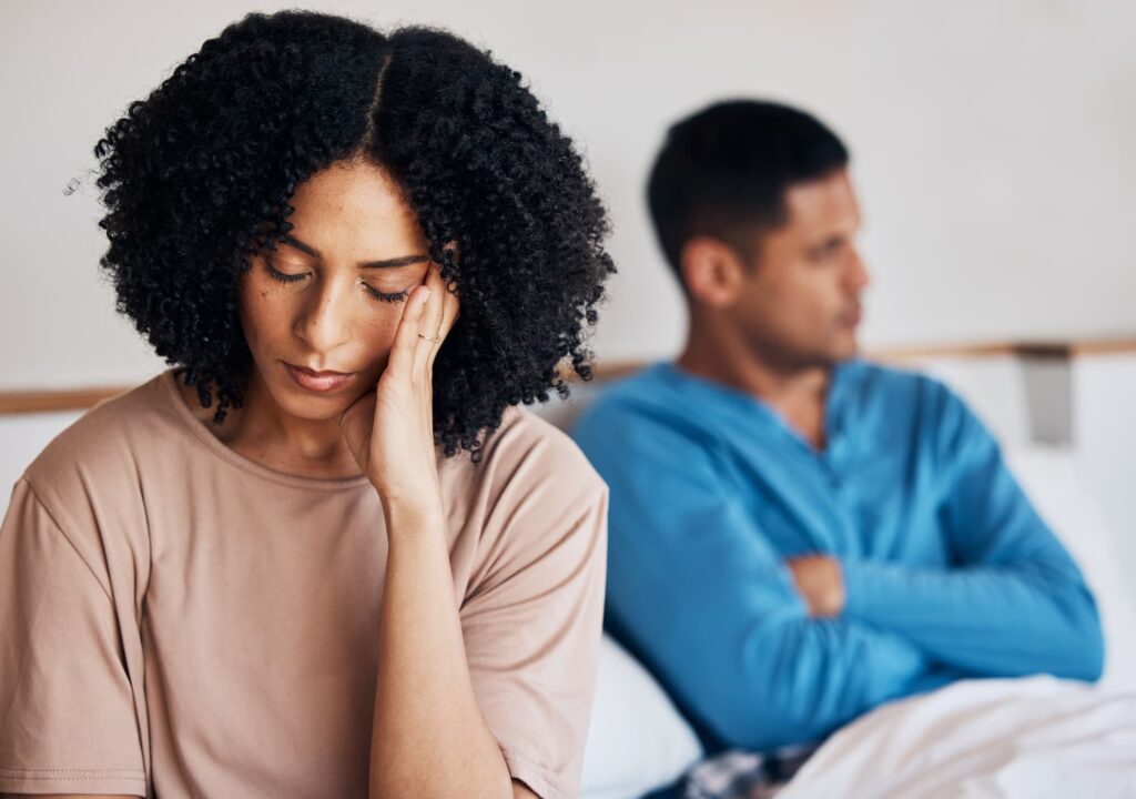 A frustrated couple sits in bed, unsure of how to find Treatment For Lower Abdominal Pain During Sex near Plano.