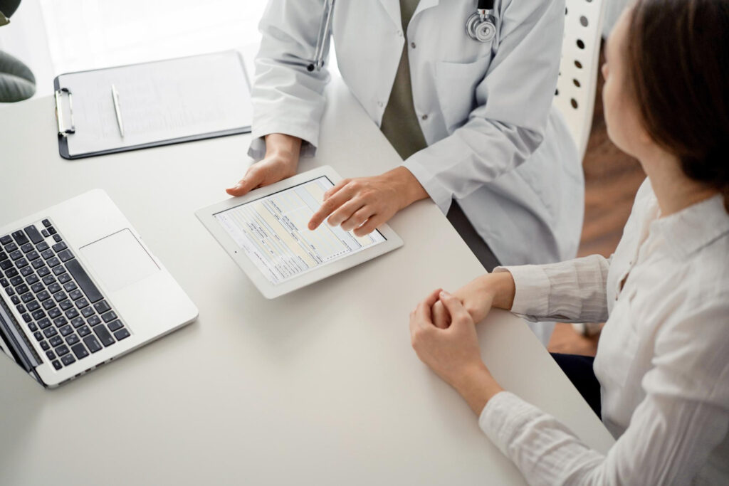 Overhead view of a doctor showing a female patient their medical results during an annual wellness exam near Plano.