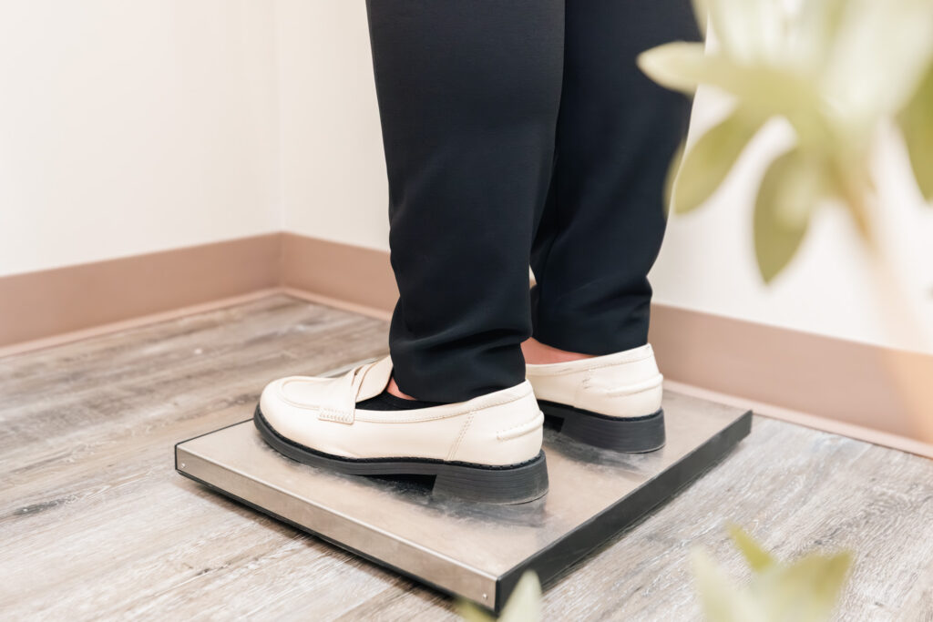 Close up of a patient standing on a scale atop a rug in a medical treatment room in Frisco.