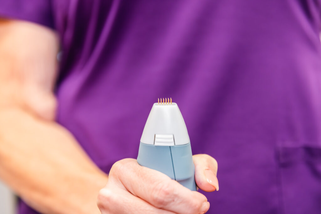 Close up of a hand showing off the tip of a hand piece of skin rejuvenation device that uses RF microneedling near Plano.