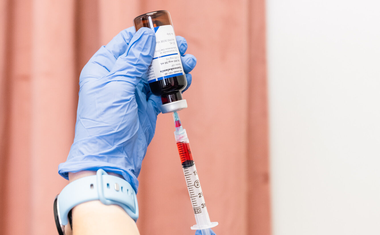 Close up of a gloved hand prepping weight loss injections in Frisco by filling the syringe with medication.